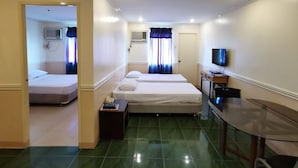 Ein Hotelzimmer mit zwei Betten, einem Fernseher, einem Schreibtisch und einem durchgegangenen Badezimmer.