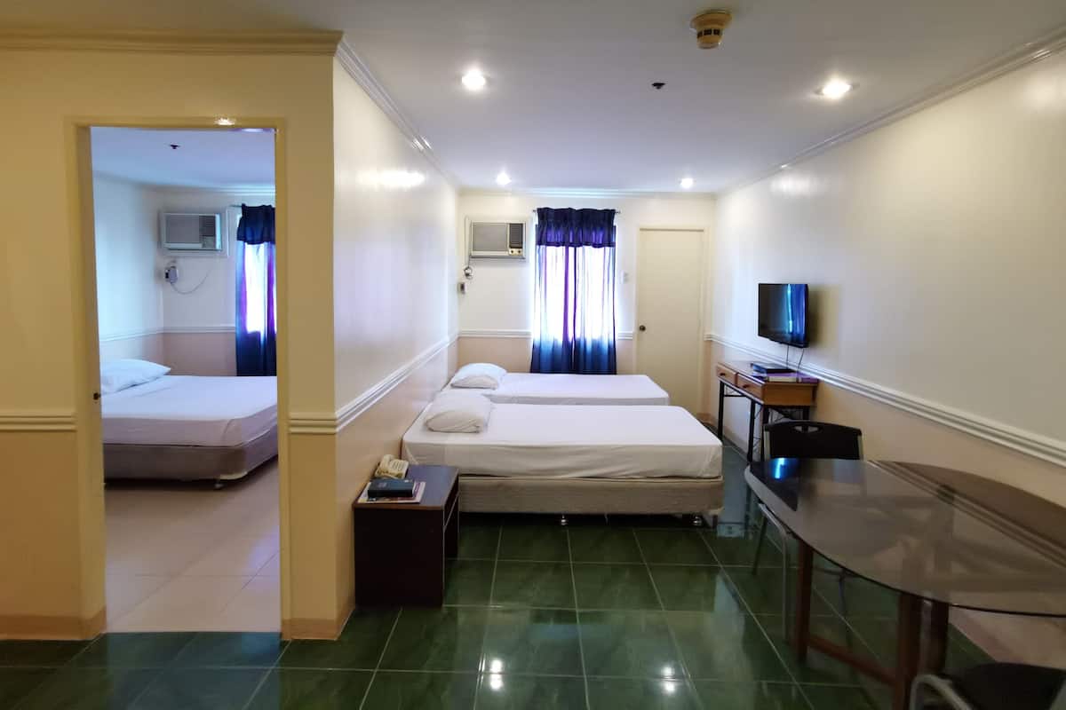 A hotel room with two beds, a TV, a desk, and a bathroom visible through an open door.