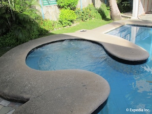 A swimming pool with a unique design, surrounded by lush greenery and a stone wall. - Metro Park Hotel Cebu City (Cebu City)