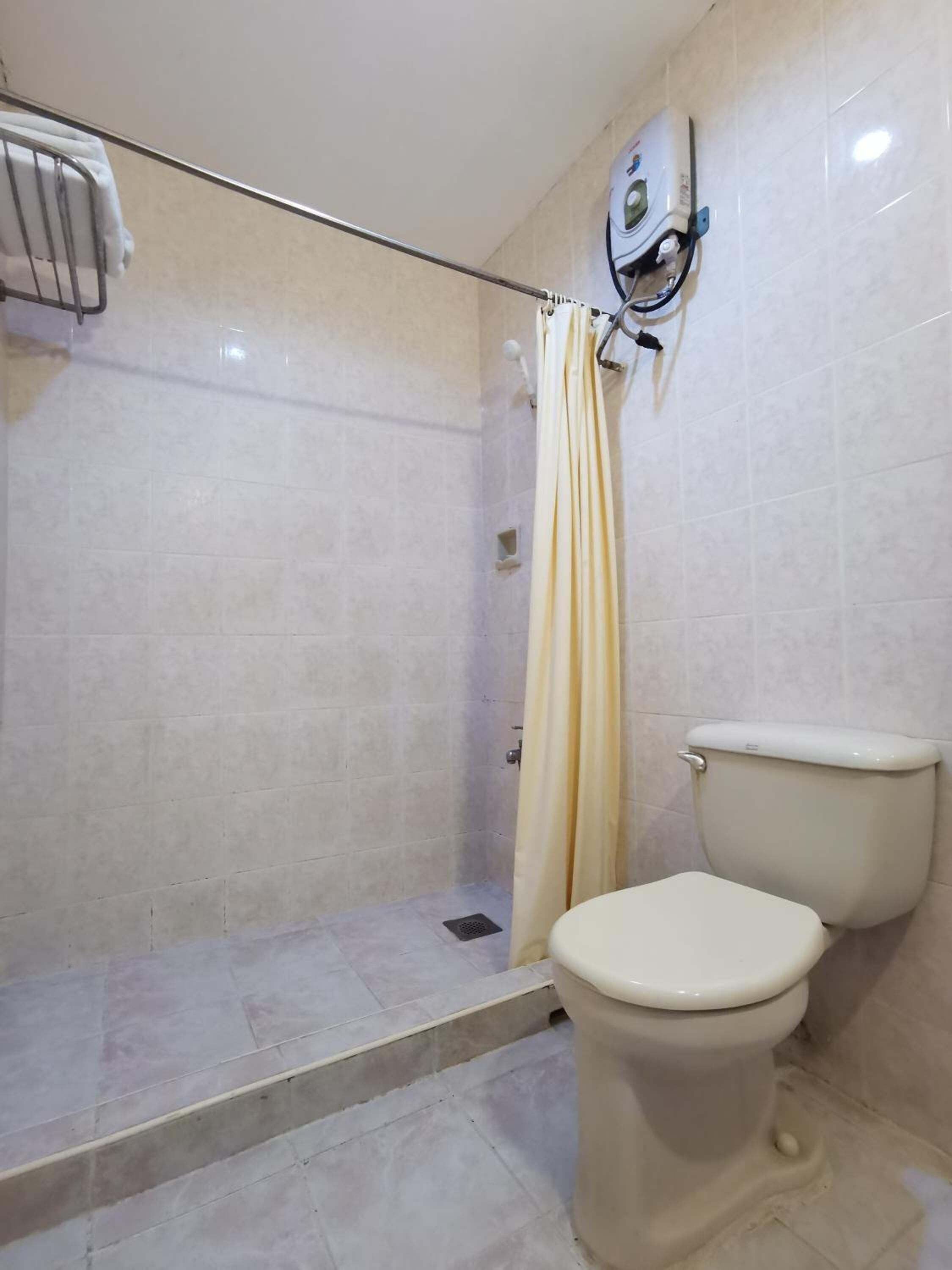 A bathroom with a shower, toilet, and a wall-mounted air purifier.