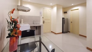 Eine kompakte Küche mit Spüle, Kühlschrank und Essbereich mit Tisch und Stühlen.