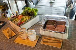 A table with a salad, a meat tray, and condiments. - Khong Chiam Orchid Riverside Resort (Khong Chiam)