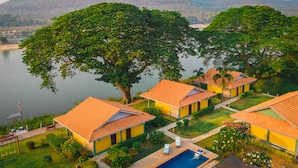 A resort with multiple yellow buildings, a swimming pool, and a view of a lake and mountains. - Khong Chiam Orchid Riverside Resort (Khong Chiam)