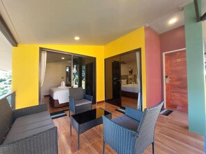A hotel room with a balcony, a bed, a bathroom, and a dining area with wicker furniture. - Khong Chiam Orchid Riverside Resort (Khong Chiam)