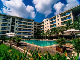 Un hotel con varias plantas, una piscina central y palmeras.