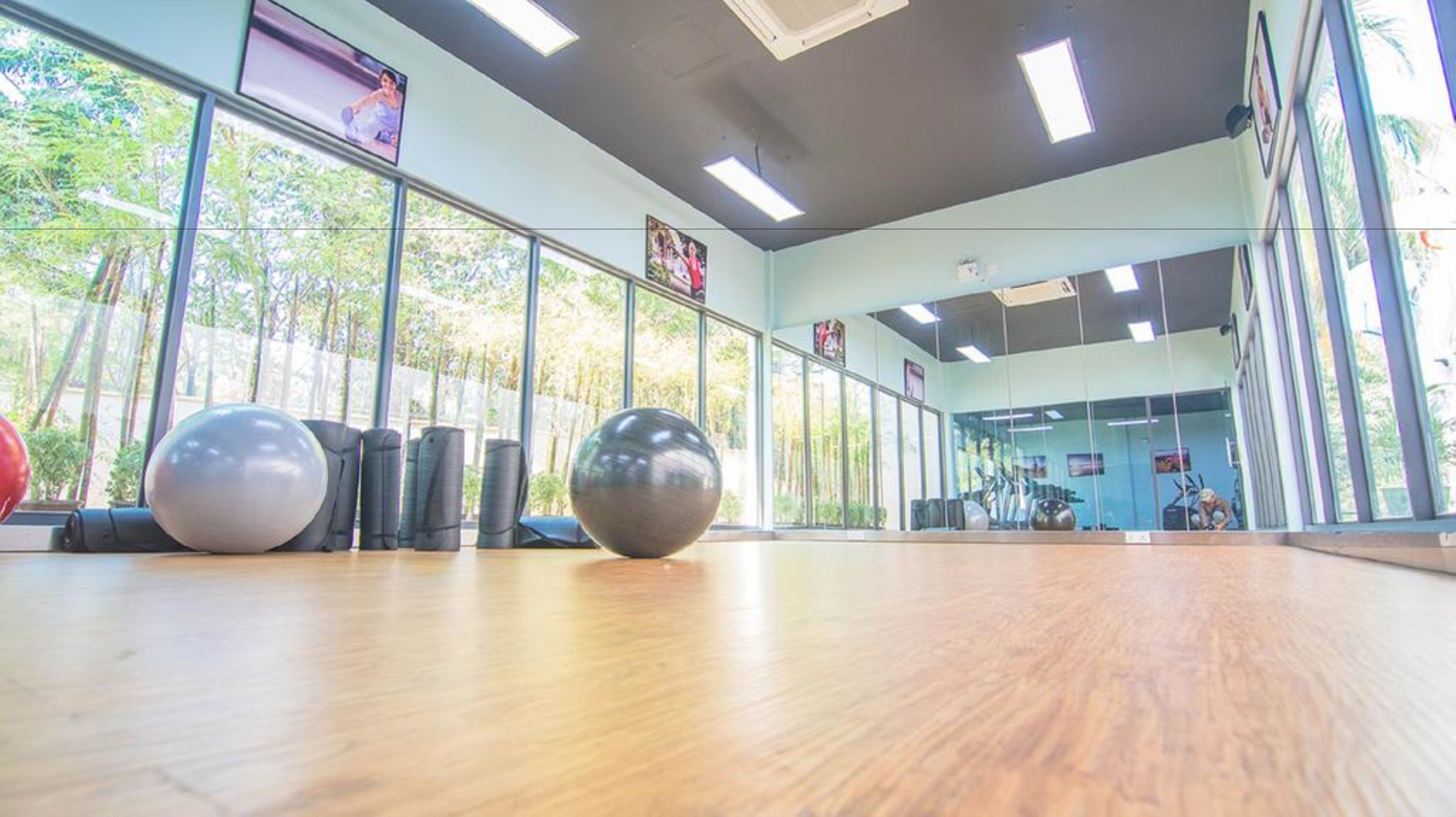 A spacious room with large windows, exercise balls, and a wooden floor.