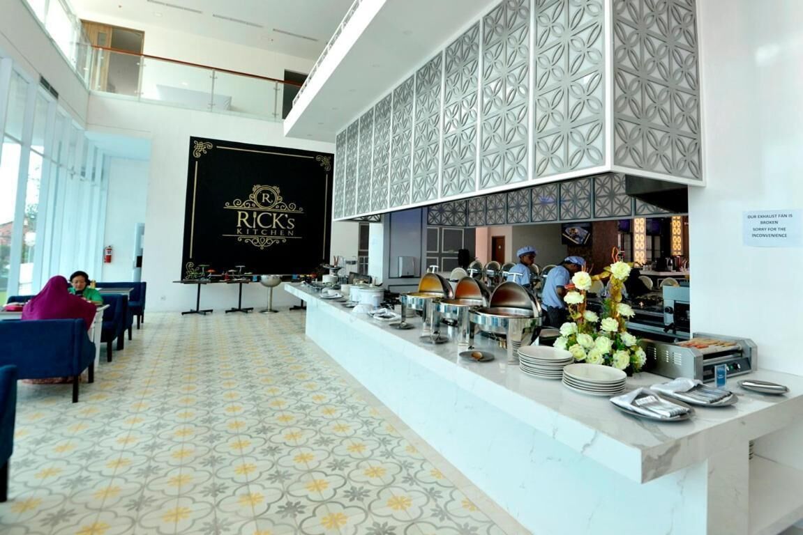 A restaurant with a buffet setup, a large screen displaying the restaurant's name, and a patterned floor.
