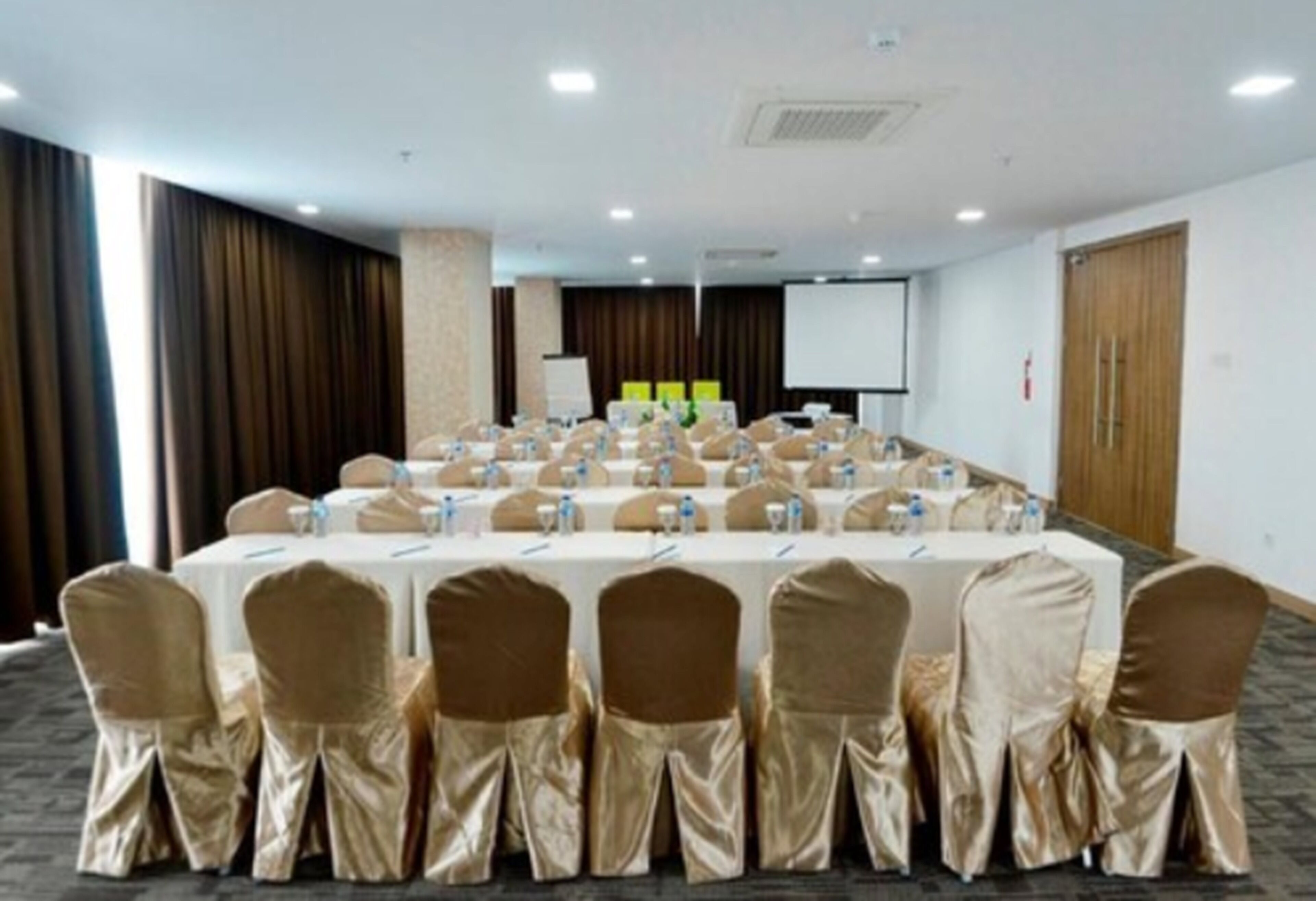 A conference room with a long table, chairs, and a projector screen.