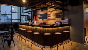 Un espace bar moderne, doté d’un comptoir, de tabourets et d’étagères remplies de bouteilles.