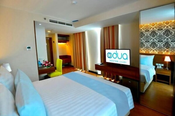 Una habitación de hotel con una cama grande, televisión, escritorio y espejo.