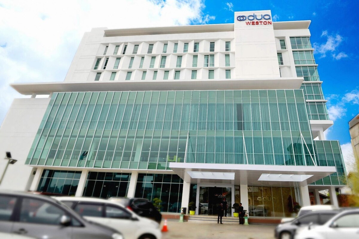 Un moderno edificio de hotel con un llamativo letrero 'DuPont', grandes ventanales y un área de entrada cubierta.
