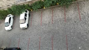 A parking area with two white cars and a black car parked. - Topaz Residence (Jakarta)