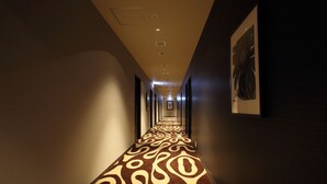 A long, narrow hallway with patterned carpet and recessed lighting. - Centurion Hotel Grand Kobe Station (Kobe)