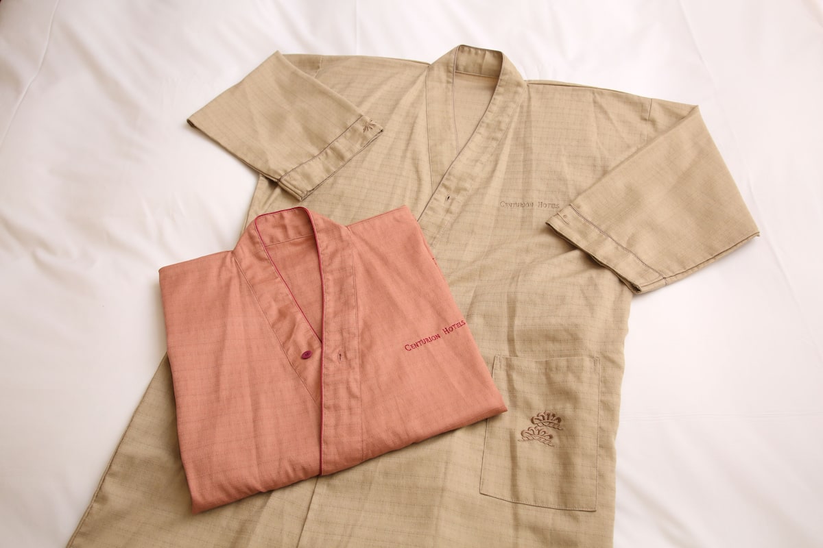 A bed with a beige bedspread and a pink shirt on it.