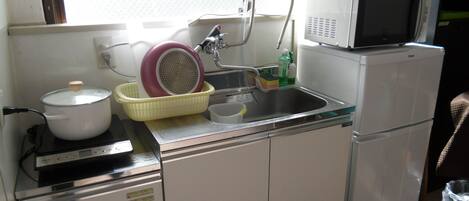 A compact kitchen with a stove, sink, and microwave.