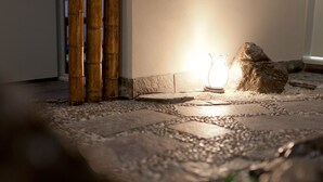 A stone pathway leading to a door with a bamboo screen and a lit lantern. - Shin-Okubo Sekitei Hotel (Tokyo)