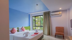 A hotel room with a bed, a chair, a window with curtains, and an air conditioning unit. - Na Tubthieng Boutique Resort (Trang)