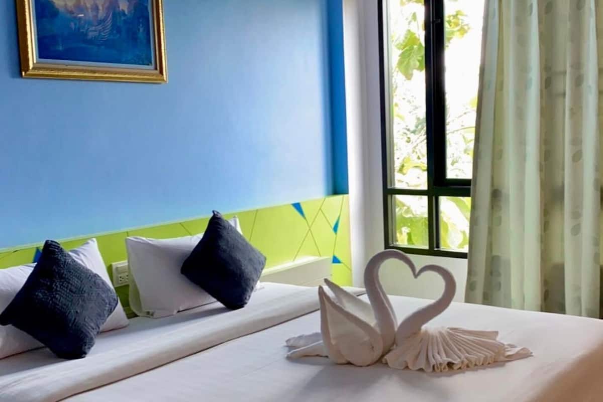Ein Hotelzimmer mit Bett, Kissen, einer herzförmigen Dekoration und einem Fenster mit Vorhängen.