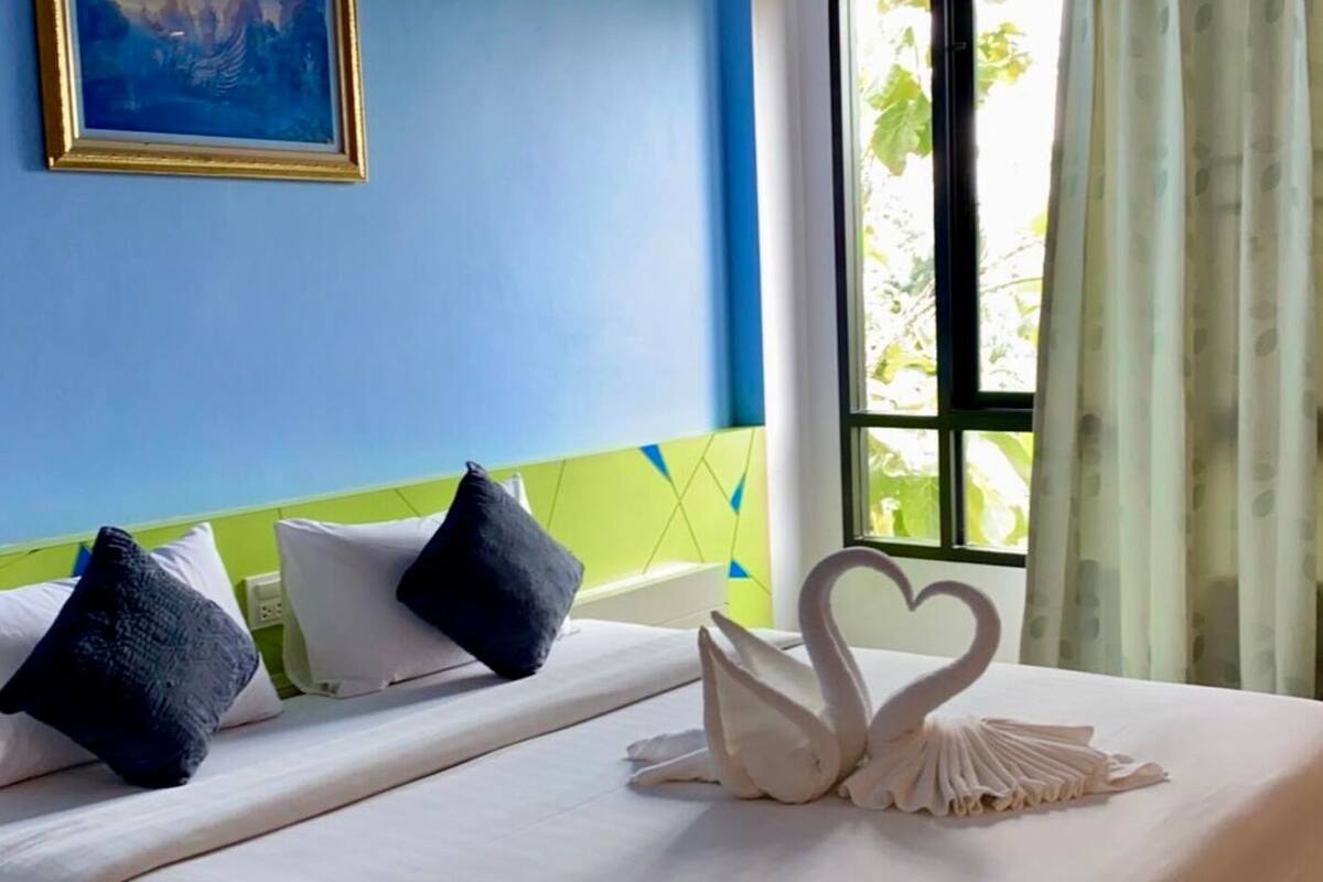 Ein Hotelzimmer mit einem Bett, Kissen und einer dekorativen Stoffschwan auf dem Bett.