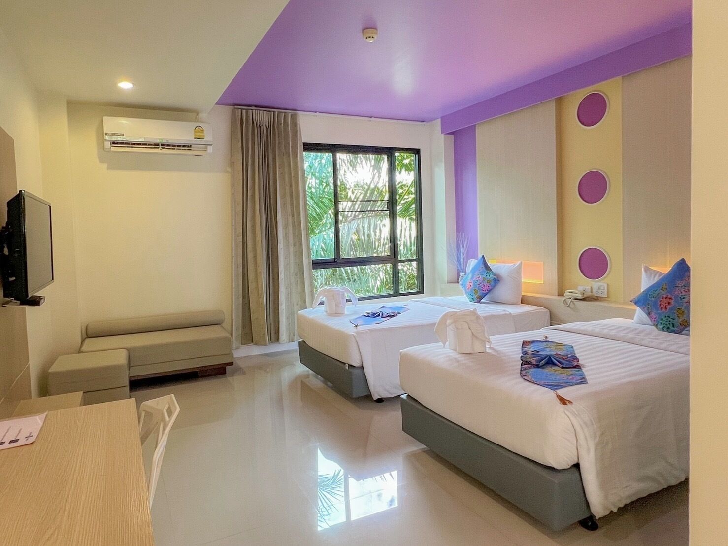 A hotel room with two beds, a TV, and a window with curtains.