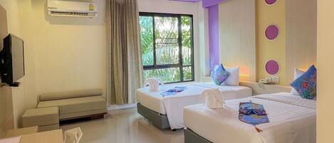 A hotel room with two beds, a TV, and a window with curtains.