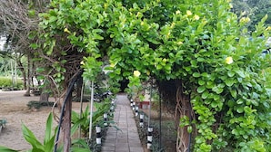 A garden pathway with a wooden walkway, surrounded by lush greenery and plants. - Secret Escape Nilaveli Ayurveda Hotel & Spa (Nilaveli)