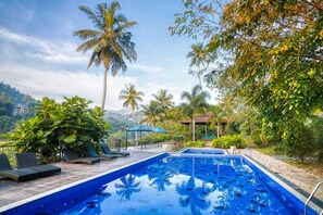 A swimming pool with lounge chairs and palm trees. - Serendip Stone Hotel and Bungalow (Kandy)