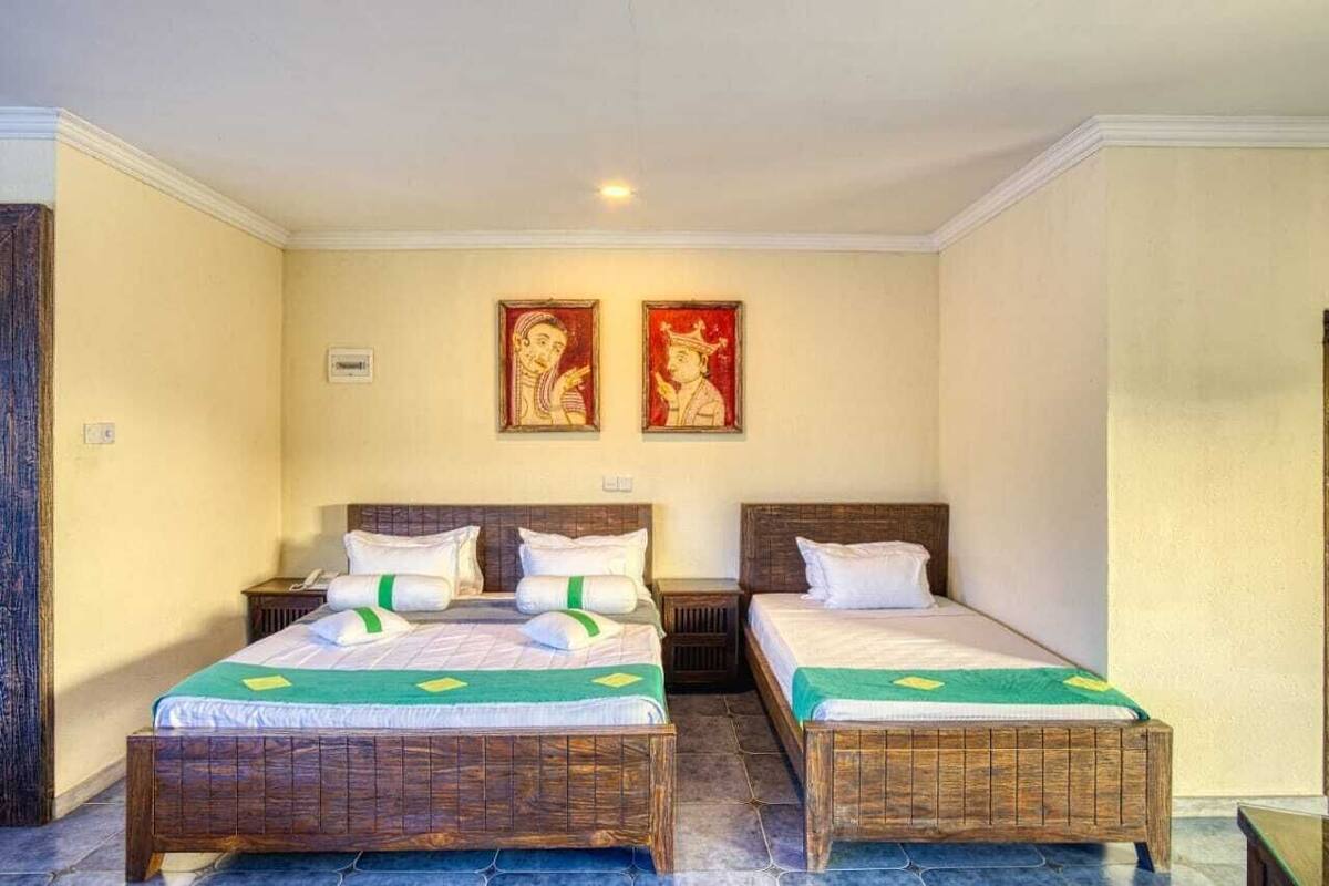 A room with two wooden beds, white bedding, and two wall-mounted paintings.