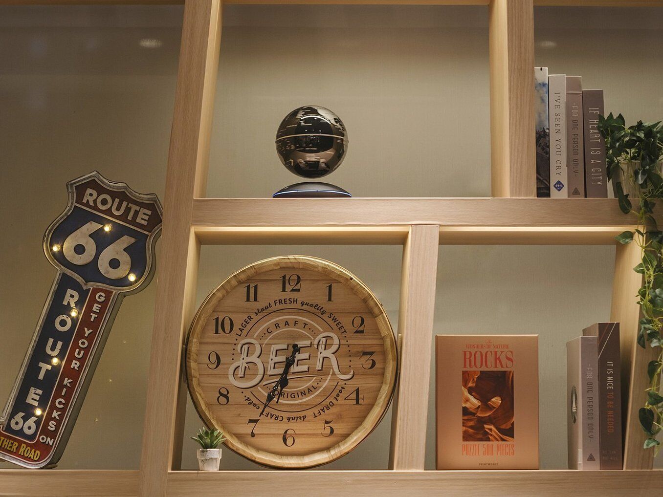 A wooden shelf with a Route 66 sign, a wooden beer clock, and a book titled "ROCKS".