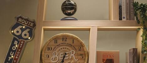 A wooden shelf with a Route 66 sign, a wooden beer clock, and a book titled "ROCKS".