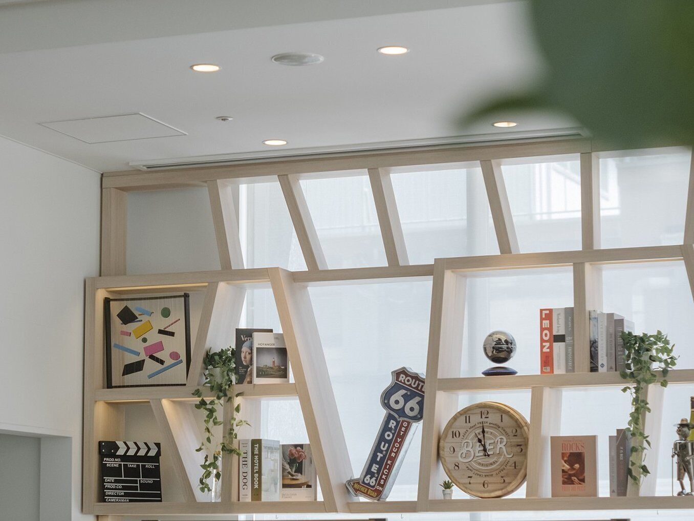 A room with a large window, a clock, and shelves with books and decorative items.