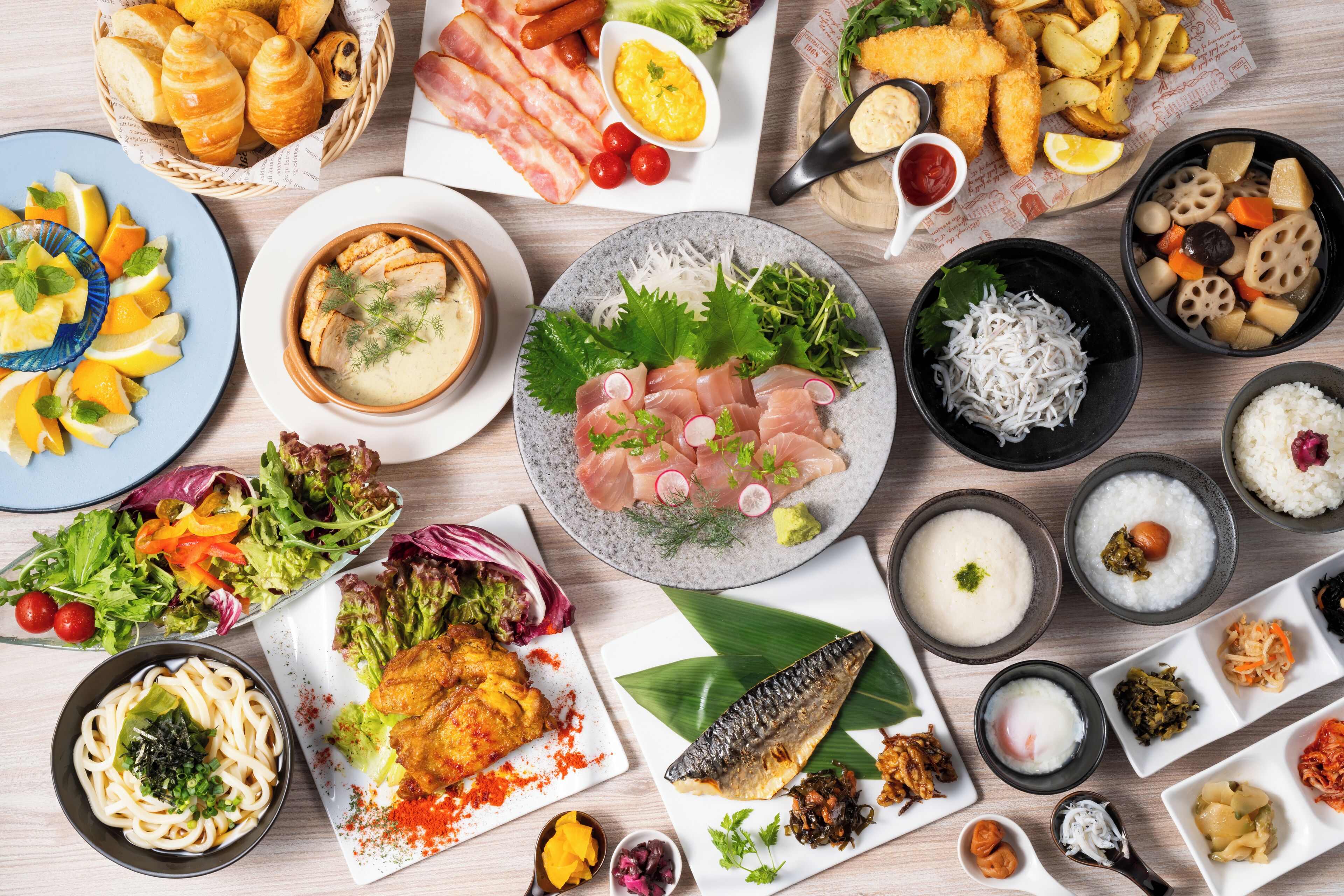 A variety of dishes including sushi, noodles, and salads, arranged on a wooden table.