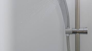 Una ducha moderna con cabezal de ducha manual y manguera flexible.