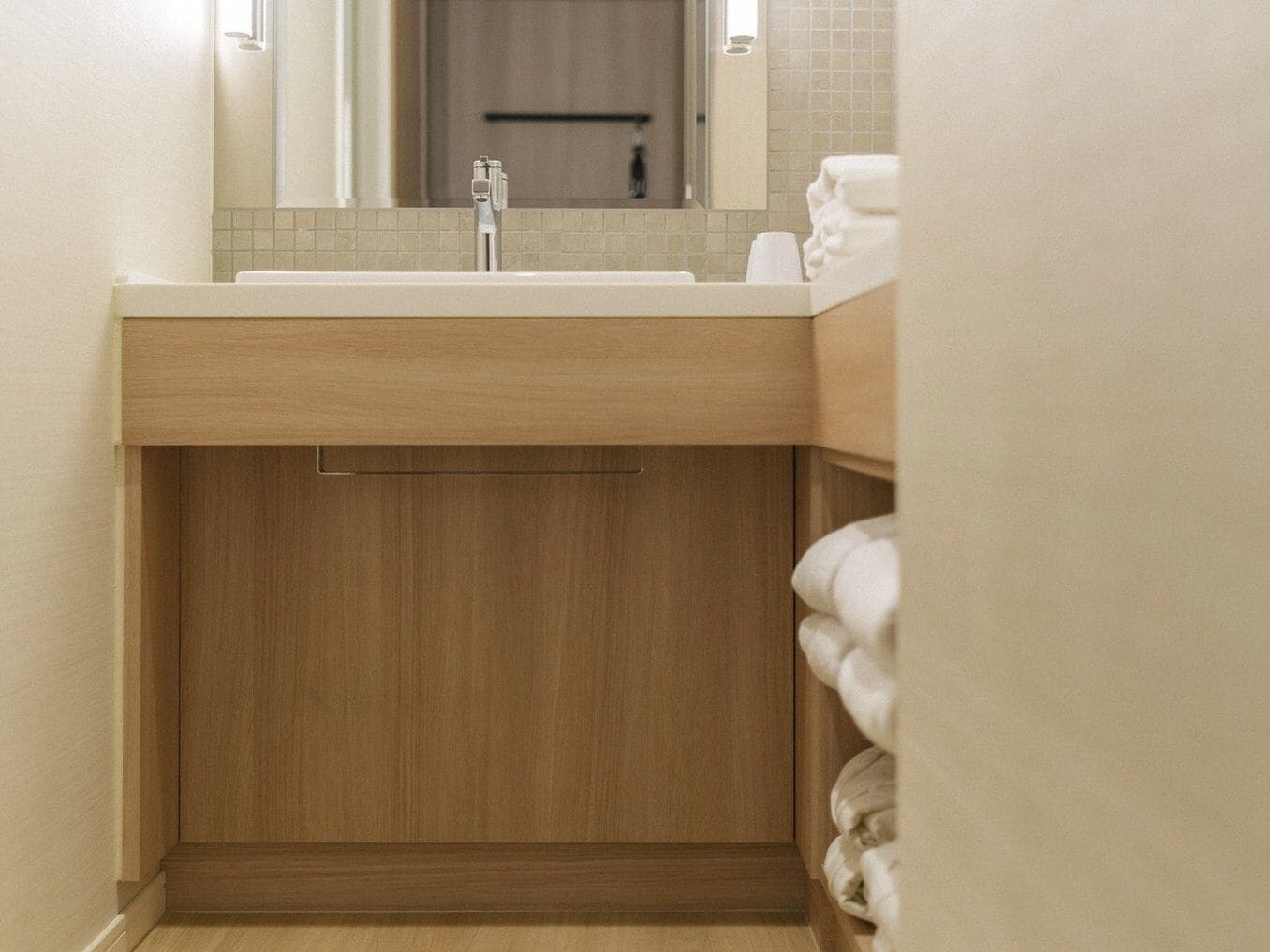 A modern bathroom with a wooden vanity, a sink, and a towel rack.
