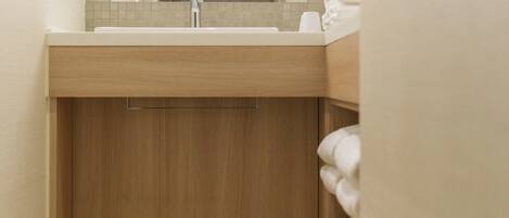 A modern bathroom with a wooden vanity, a sink, and a towel rack.