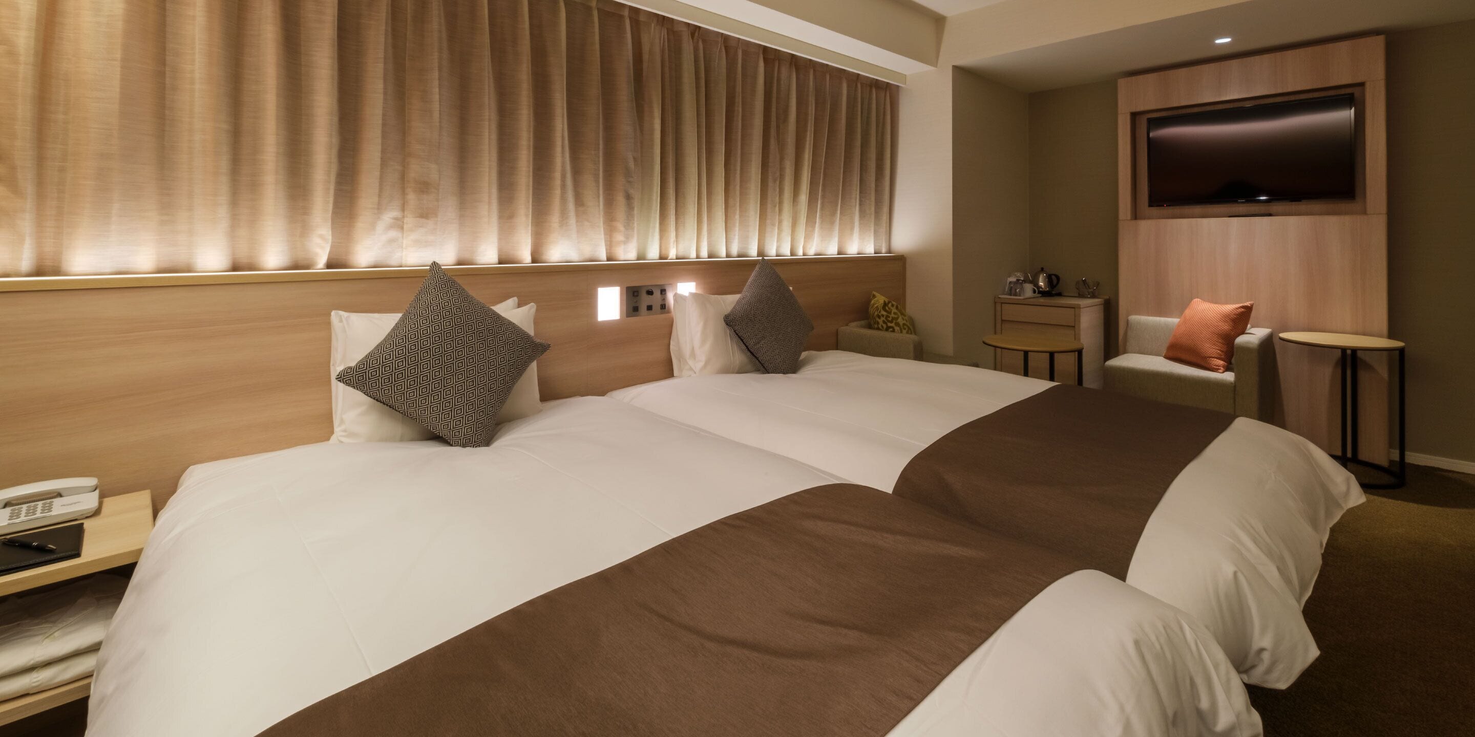 Una habitación de hotel con una cama grande, un televisor montado en la pared, una mesita y una silla.