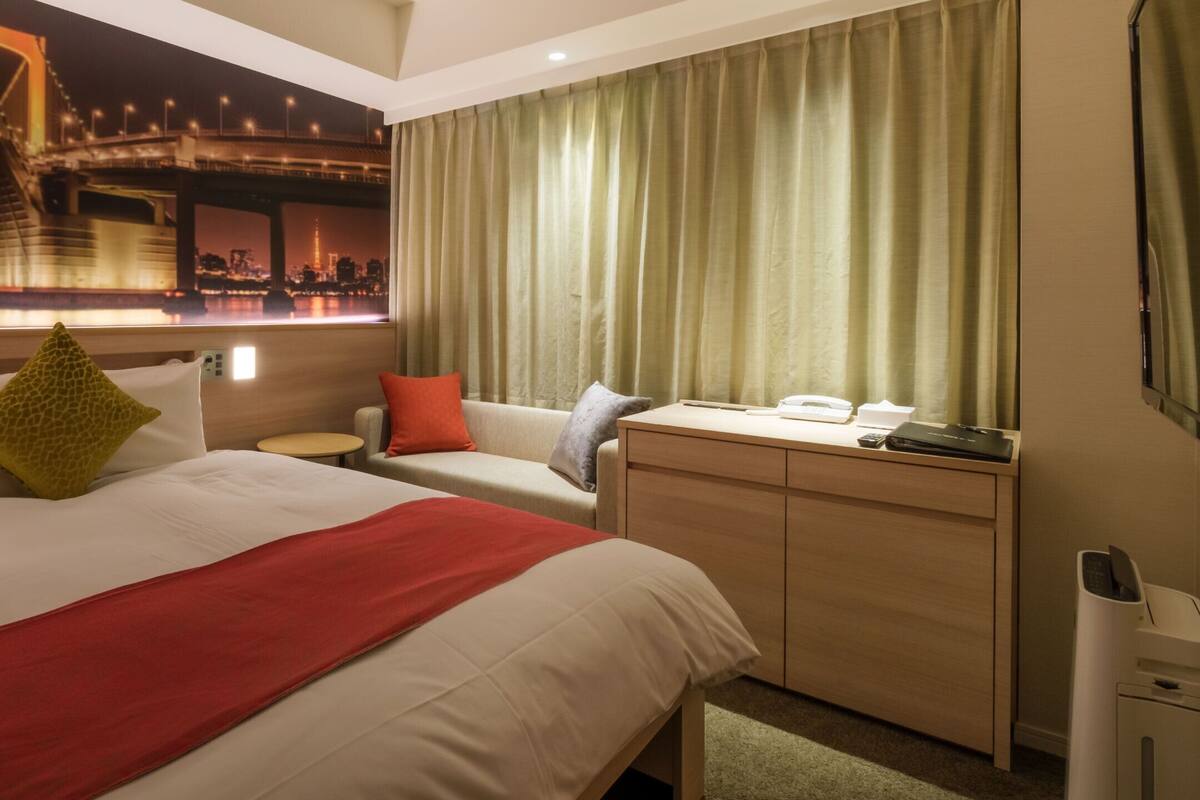 Ein Hotelzimmer mit Bett, Schreibtisch, Stuhl und Blick auf eine Brücke.