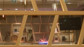 A modern interior with a 'Welcome' sign, wooden shelves, and a television.