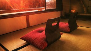 Habitación con esteras de tatami y vistas a una cerca de madera y un árbol.