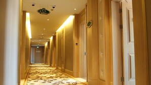 A hotel hallway with a patterned carpet, wooden paneling, and doors on one side. - Shanghai Waigaoqiao Free Trade Zone Vienna Hotel (Shanghai)