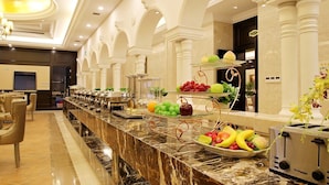 A buffet setup with various fruits and beverages, marble countertops, and a modern interior design. - Shanghai Waigaoqiao Free Trade Zone Vienna Hotel (Shanghai)