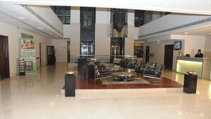 A spacious lobby with a central seating area, a reception desk, and a large window overlooking the interior. - Royal Park (Kakinada)