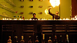 A bar with bottles of alcohol and glasses on shelves. - Royal Park (Kakinada)