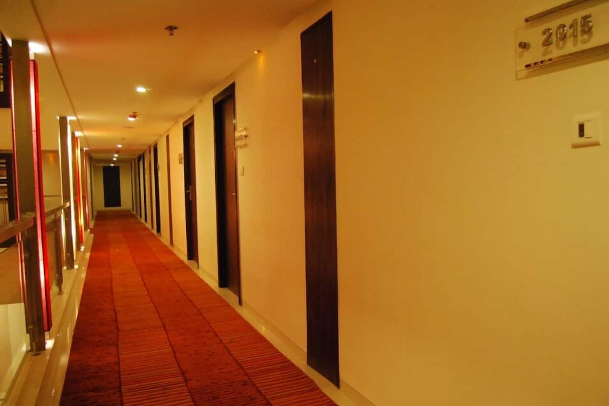 A hotel hallway with a red carpet, doors, and a sign indicating room number 2015.