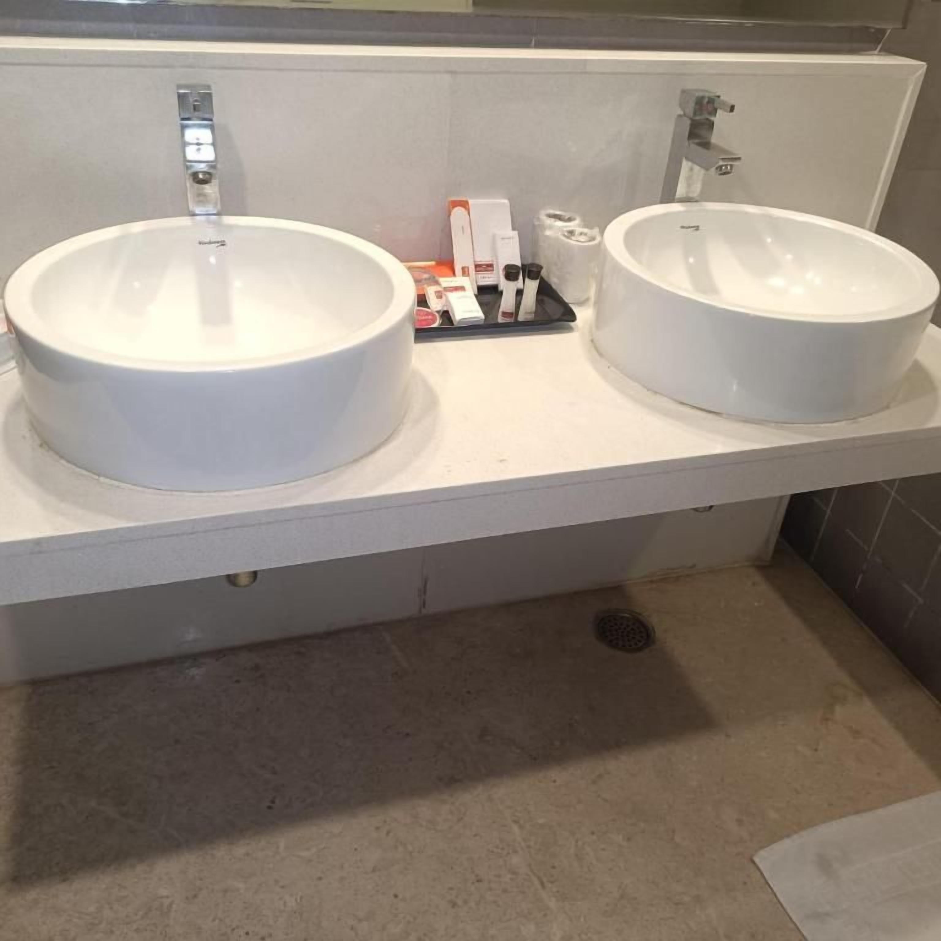 Un baño con dos lavamanos de cerámica blanca, un dispensador de toallas y un dispensador de jabón sobre la encimera.