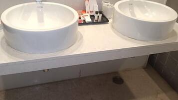 Un baño con dos lavamanos de cerámica blanca, un dispensador de toallas y un dispensador de jabón sobre la encimera.