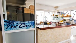 A kitchen with a stone backsplash, a wooden countertop, and a sign that reads "Port Corona". - Hostal Port Corona (Capdepera)