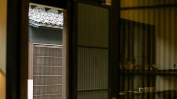A traditional Japanese room with tatami flooring, a shoji screen door, and a sliding door leading to a balcony with a tiled roof.