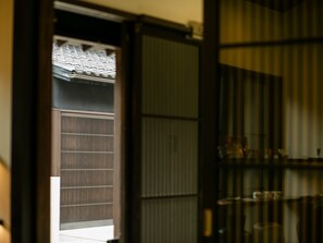 A traditional Japanese room with tatami flooring, a shoji screen door, and a sliding door leading to a balcony with a tiled roof. - Makino Oto Kanazawa (Kanazawa)