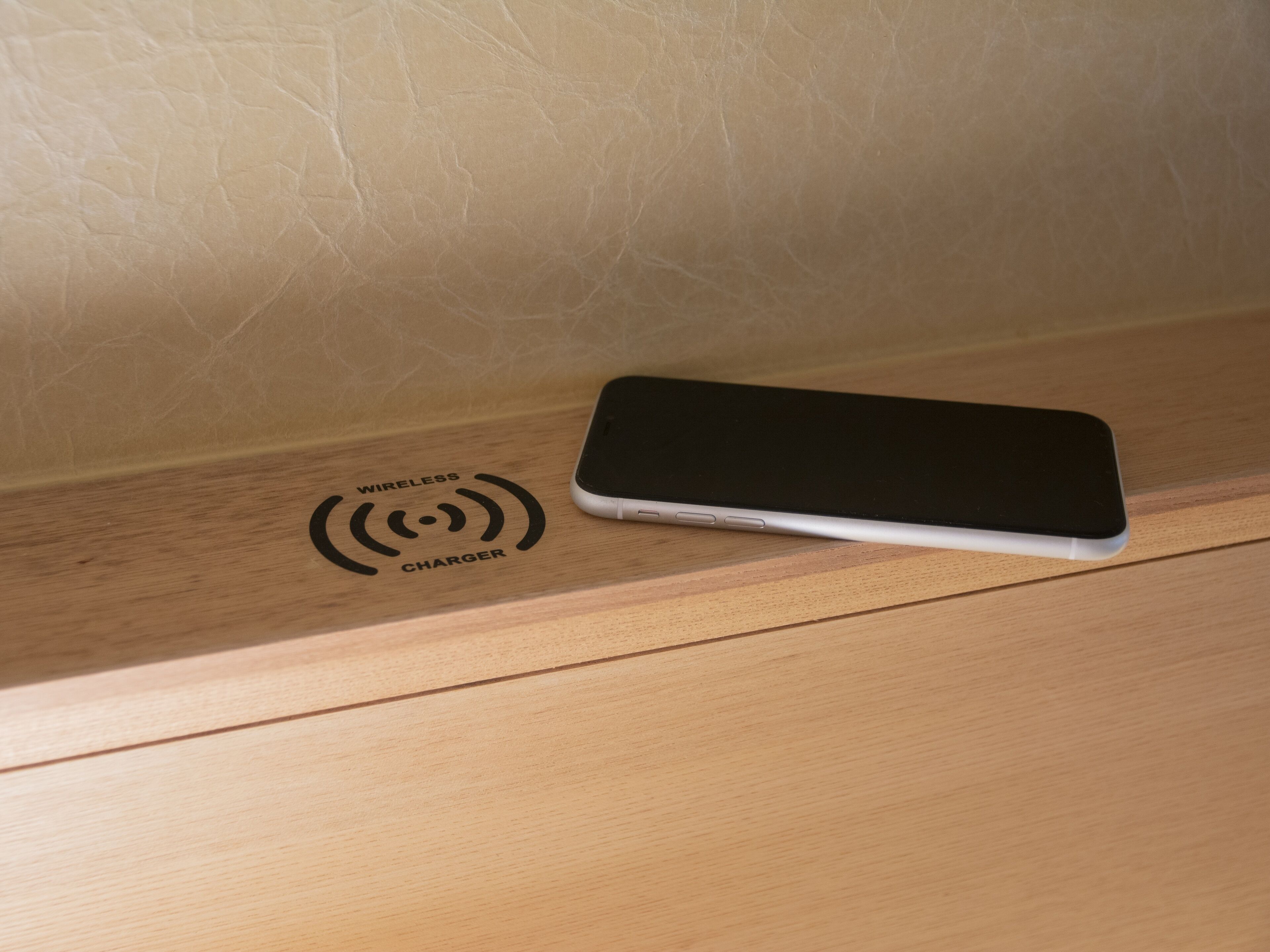 A smartphone on a wooden surface with a wireless charger symbol.